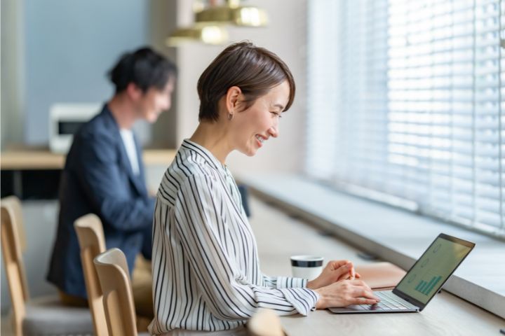 カフェのような空間でパソコン作業をする女性の画像